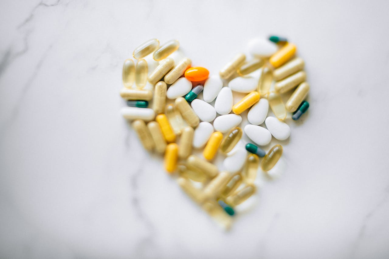 Colorful pills arranged in heart shape on a marble surface, symbolizing health and wellness.