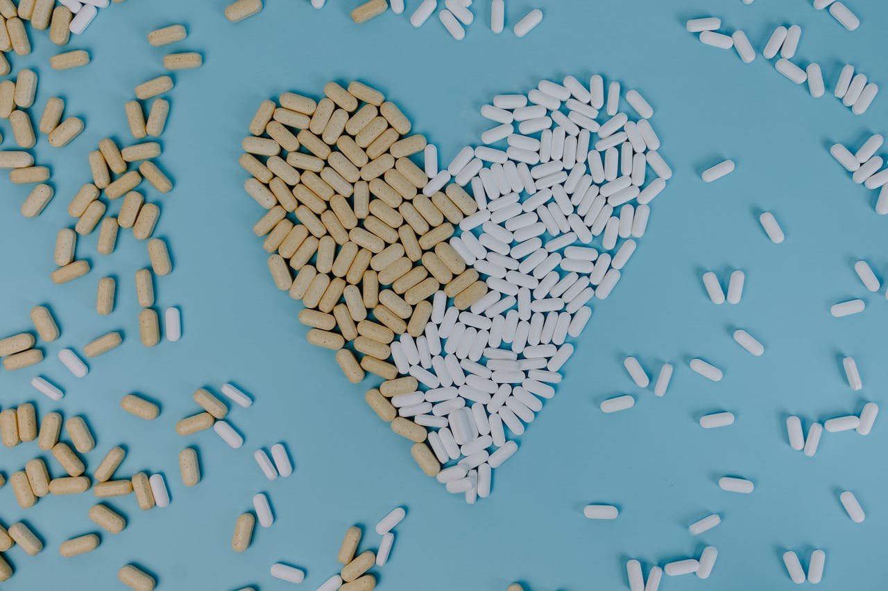 Heart-shaped design made of pills and tablets on a blue background, symbolizing health and medicine.